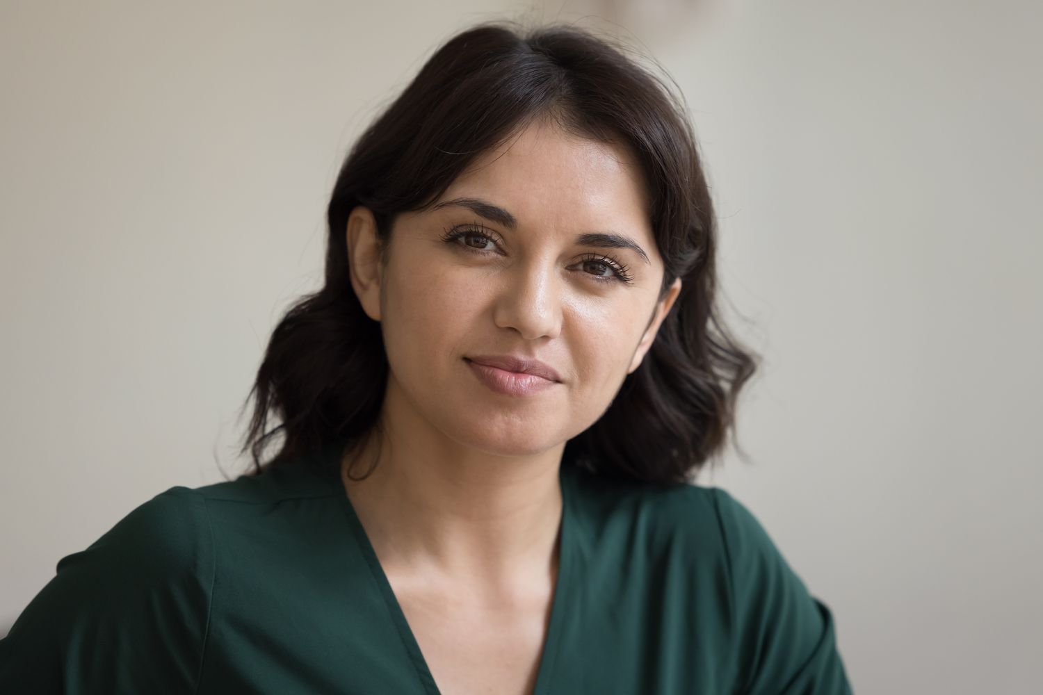 Woman with dark hair, smiling softly at camera.