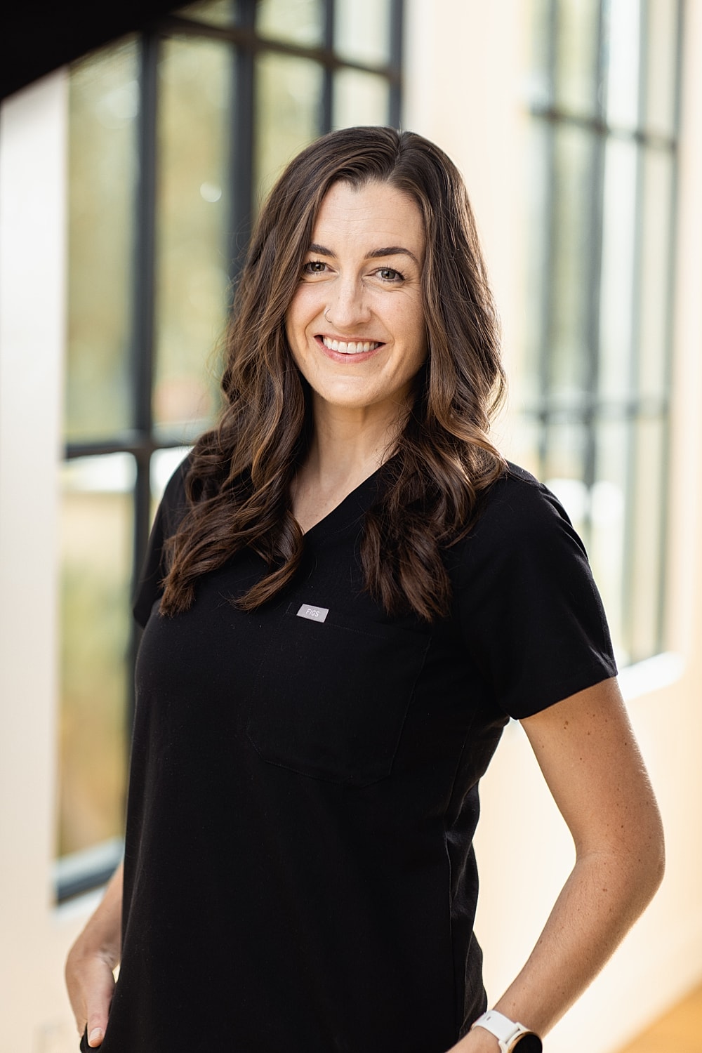 Smiling woman in a black medical scrub uniform.