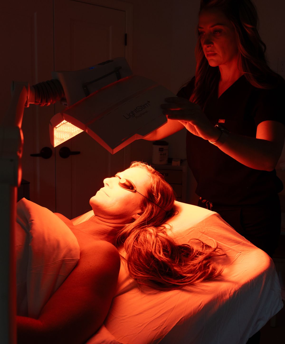 Woman receiving red light therapy treatment.
