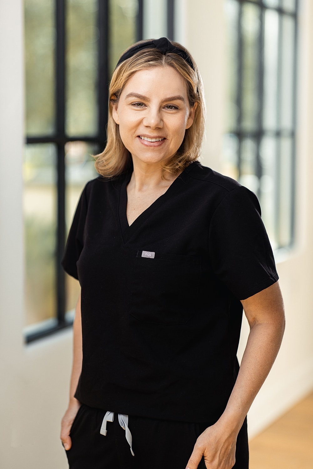 Smiling woman wearing black scrubs indoors.