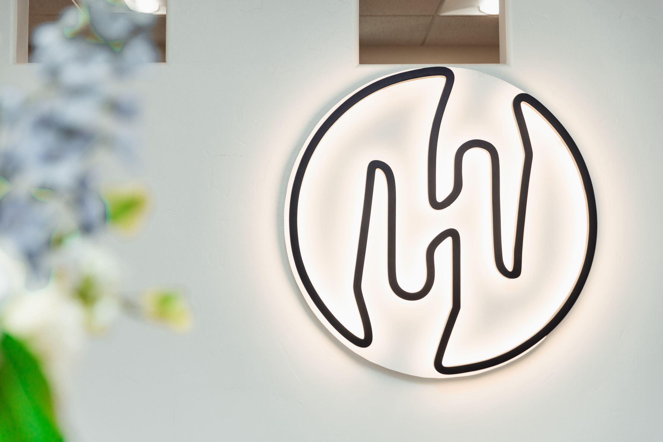 Illuminated logo on a white wall.