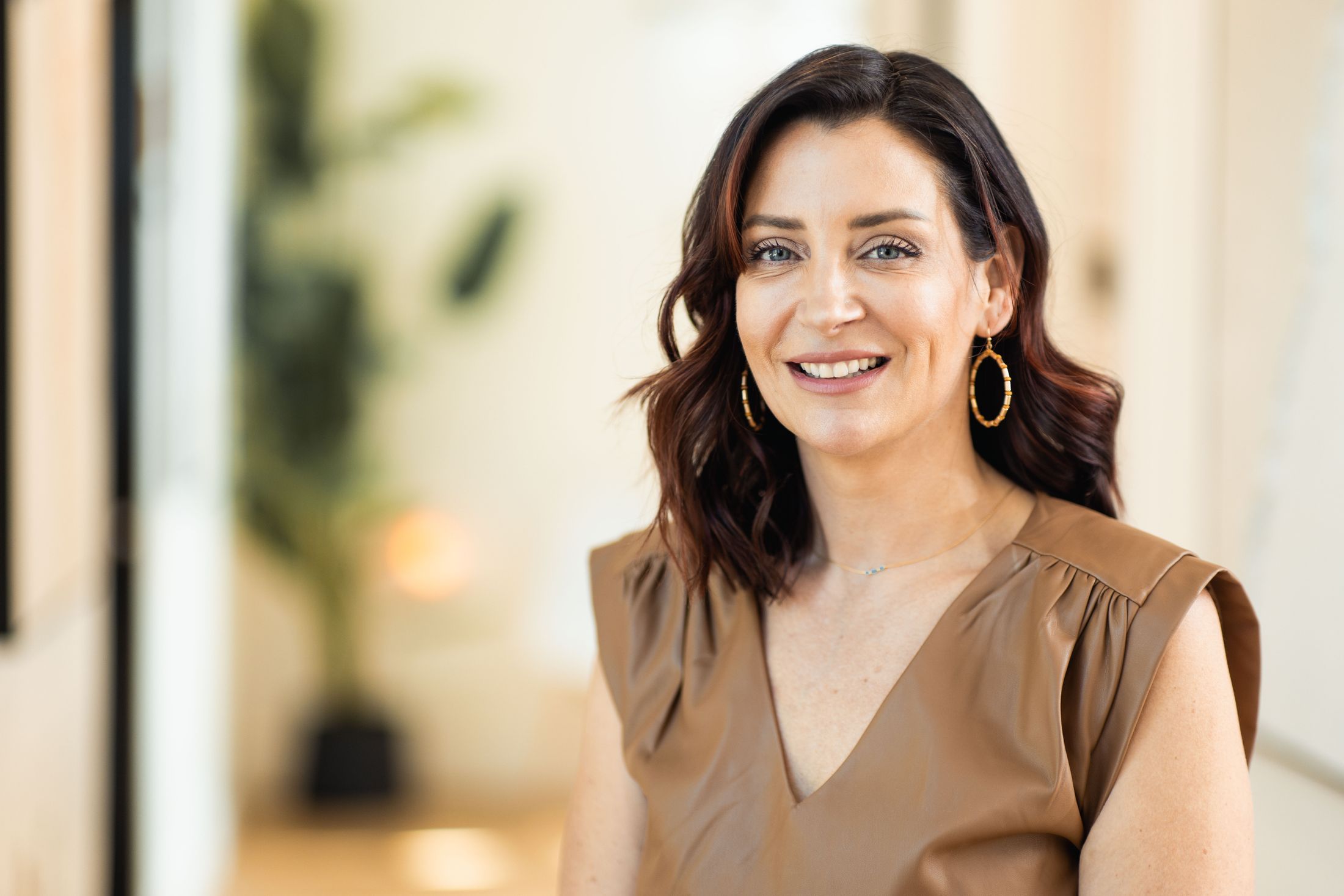 Woman smiling in a stylish outfit indoors.